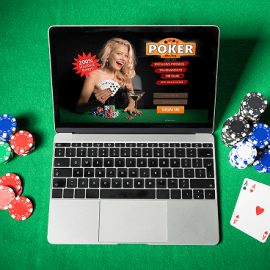 A computer on a casino table game with cards dices and coins around