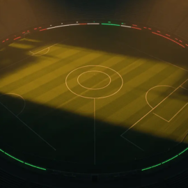 Aerial view of floodlit football pitch with golden stadium lighting and green, white, red colour accents.