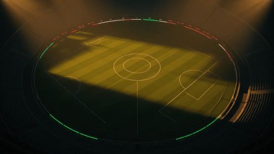 Aerial view of floodlit football pitch with golden stadium lighting and green, white, red colour accents.