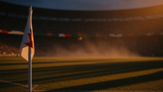 Floodlit stadium pitch at dusk with long shadows, corner flag in focus, packed stands in background.