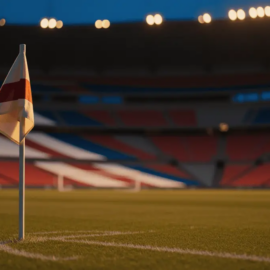 Empty floodlit stadium corner section with red, white and blue illuminated stands under evening lights.